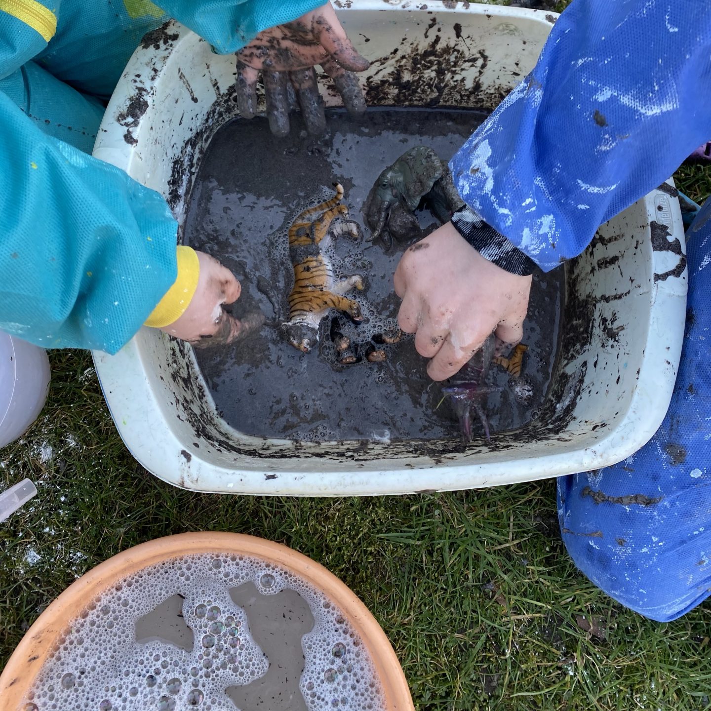 March activities for kids with mud and cornflour in a basin with plastic Schleich animals in it