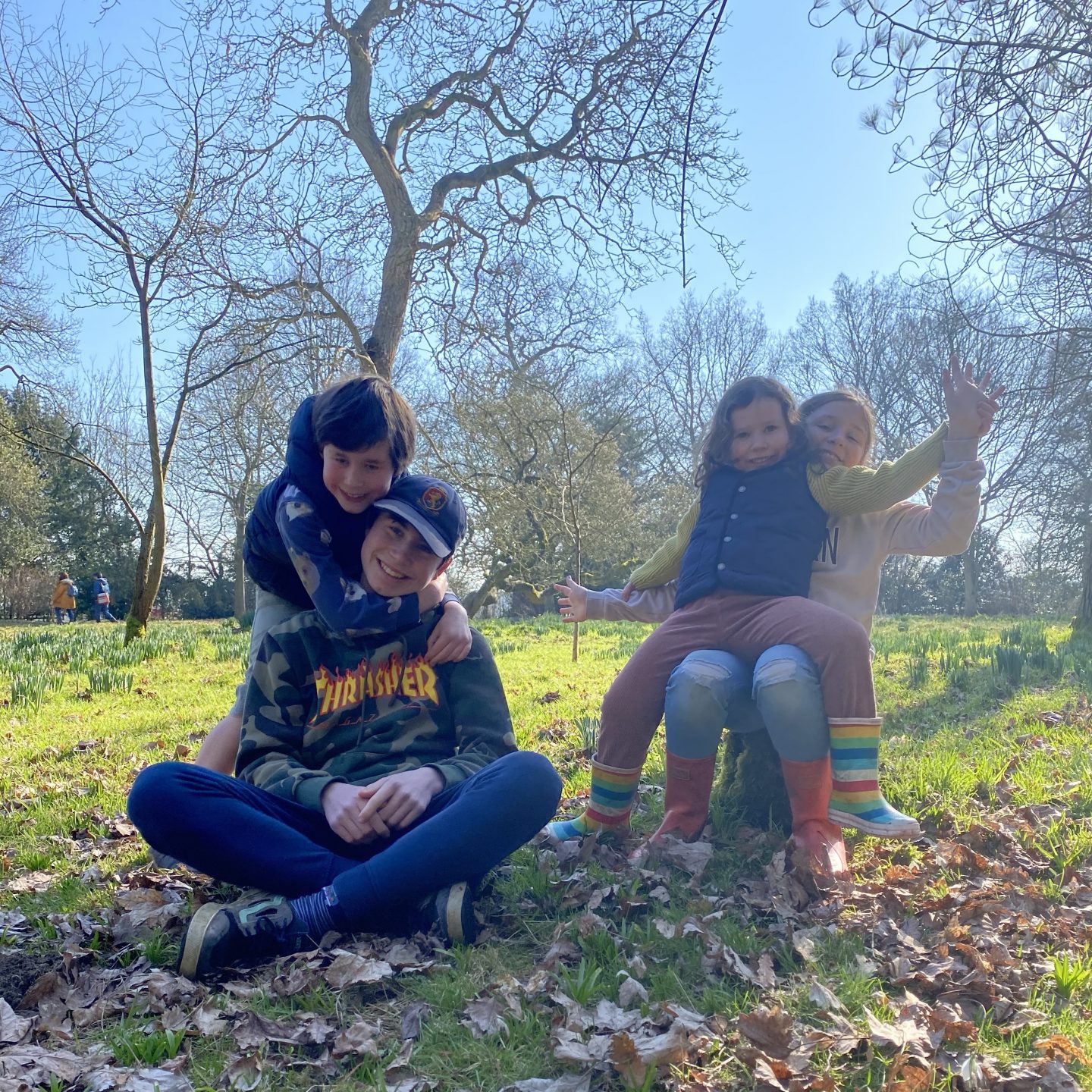 4 children smiling and hugging in the park as springtime is coming