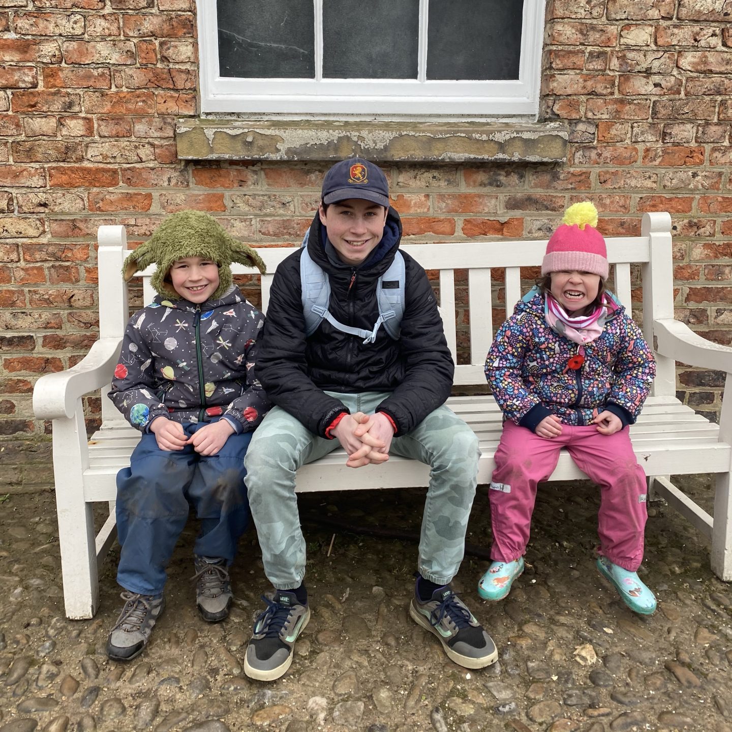 3 children sat on a bench smiling on a slow half term week