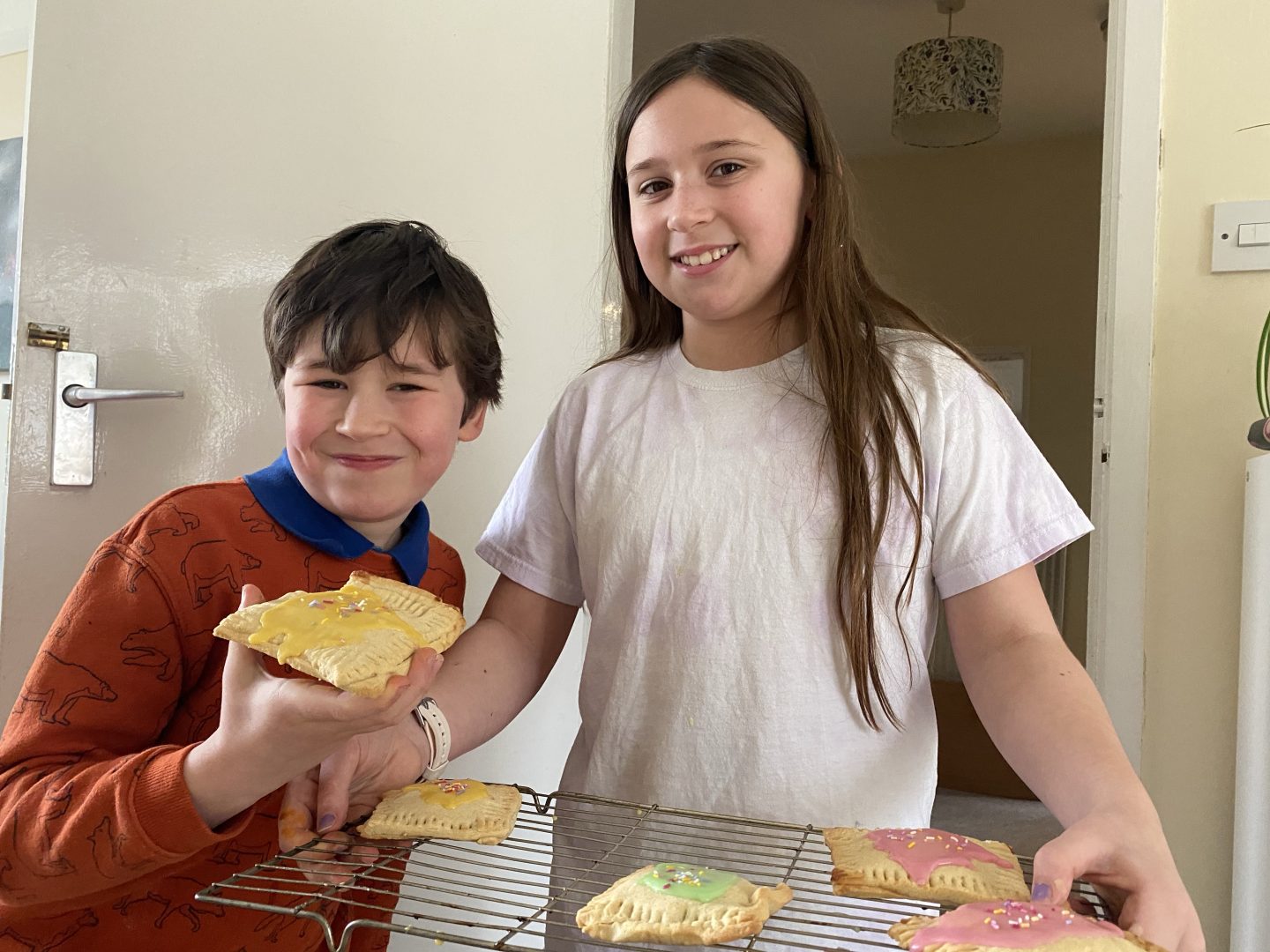 2 children holding a tray of biscuits