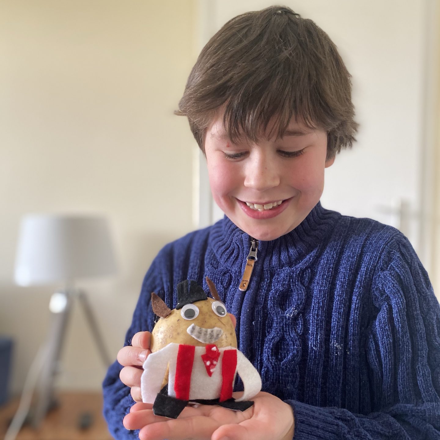 a boy holding a potato which has been decorated for a Homeschool activity