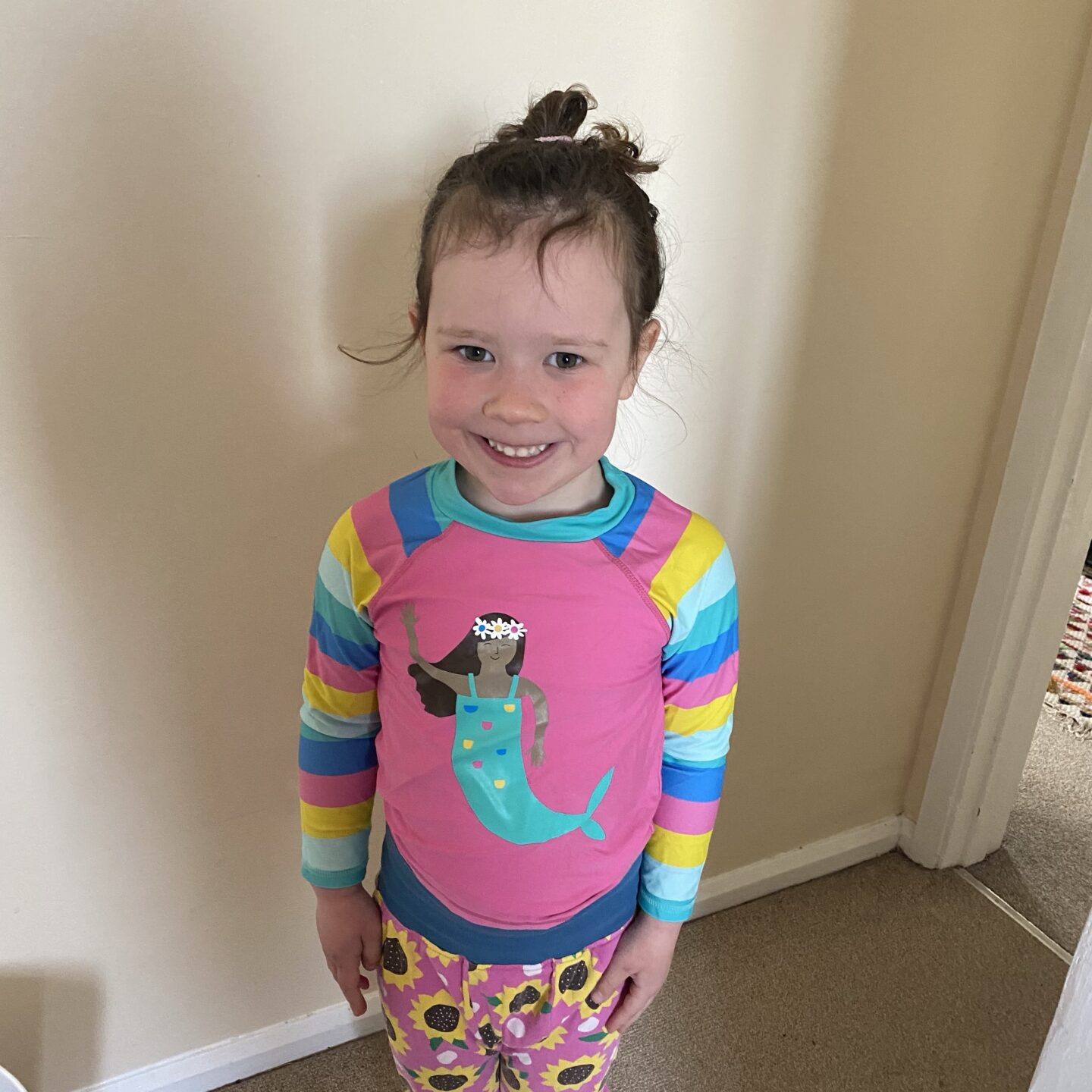 A young girl smiling at the camera with a long mermaid tash vest