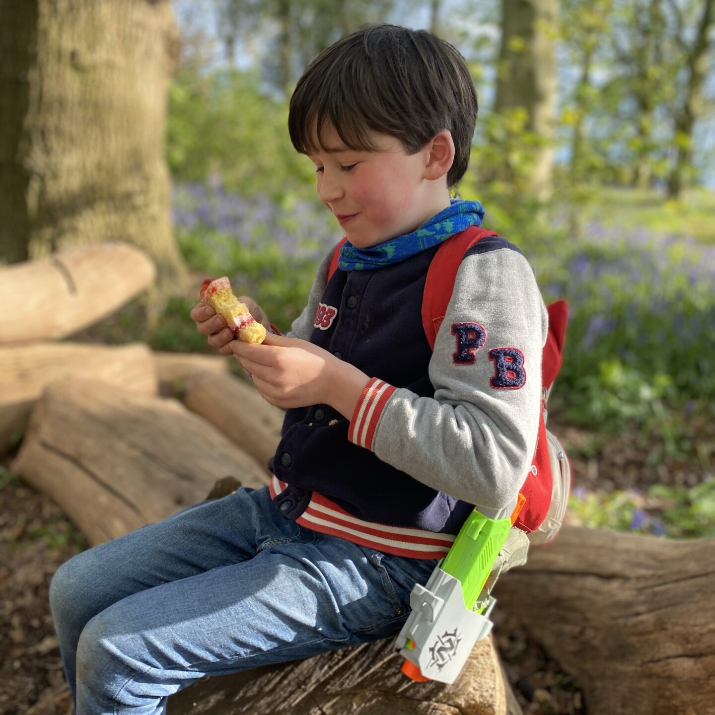 a boy sat on a log eating cake