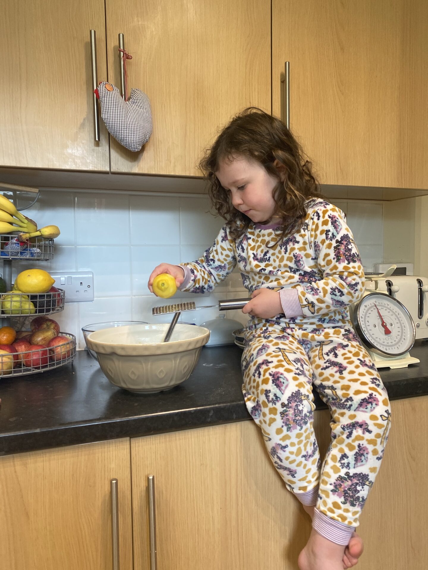 Rainy may days with a small girl zesting a lemon into a baking bowl
