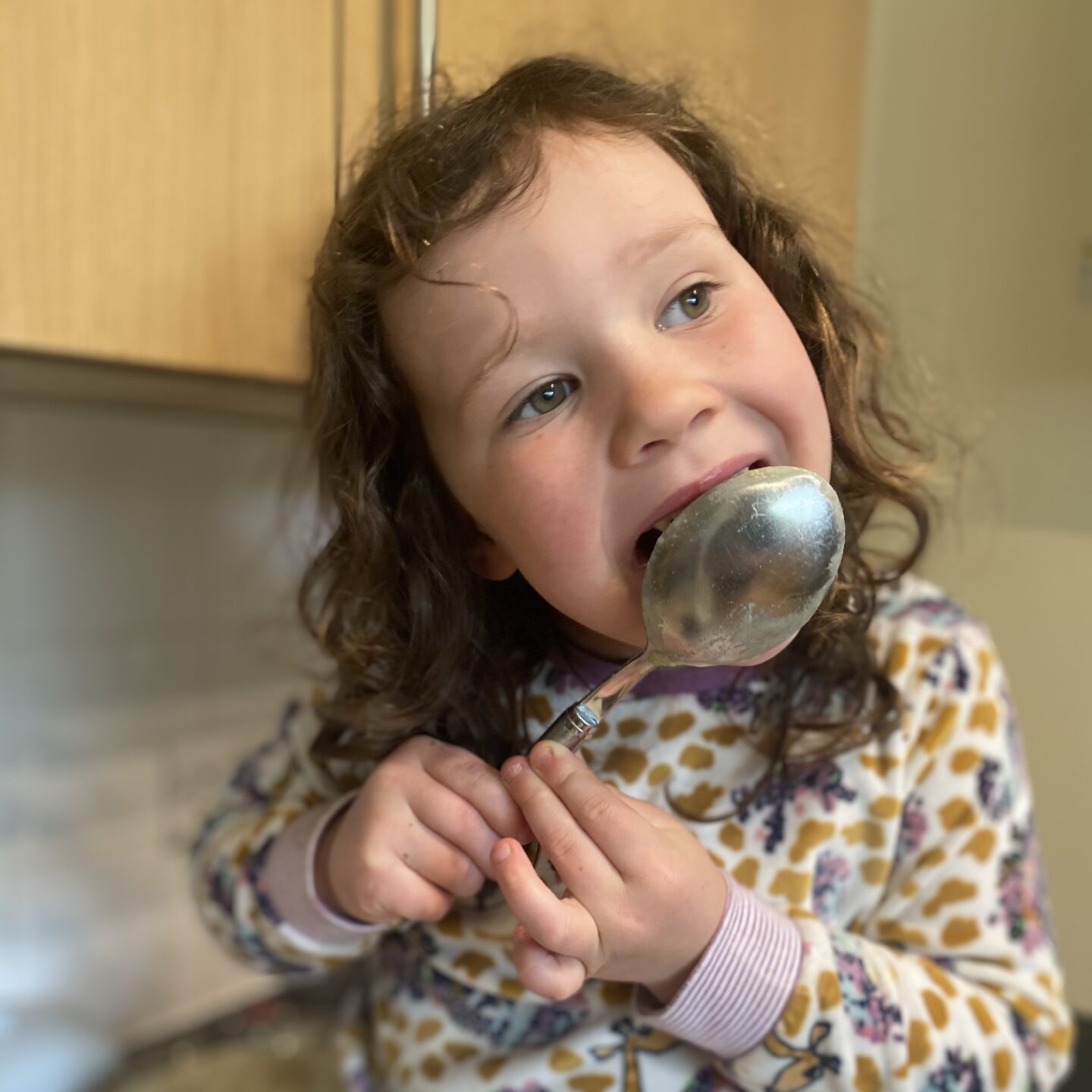 a girl licking the baking spoon