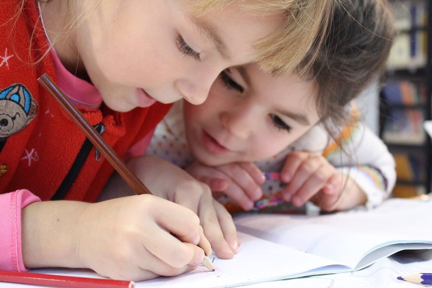 Top tips for choosing a school for your child with two children sat writing at a desk 