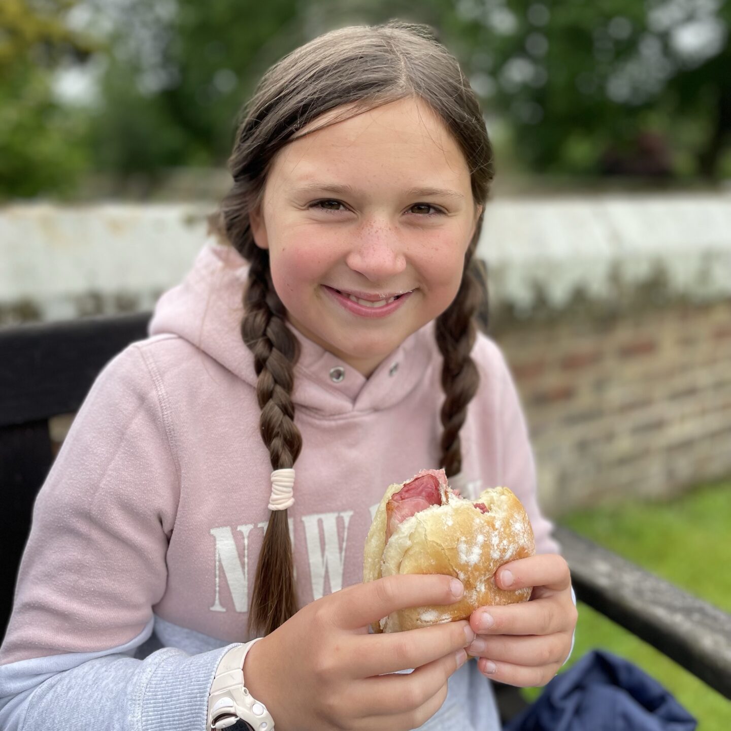 a girl eating a bacon sandwich on a bench whilst visiting the Howardian Hills 