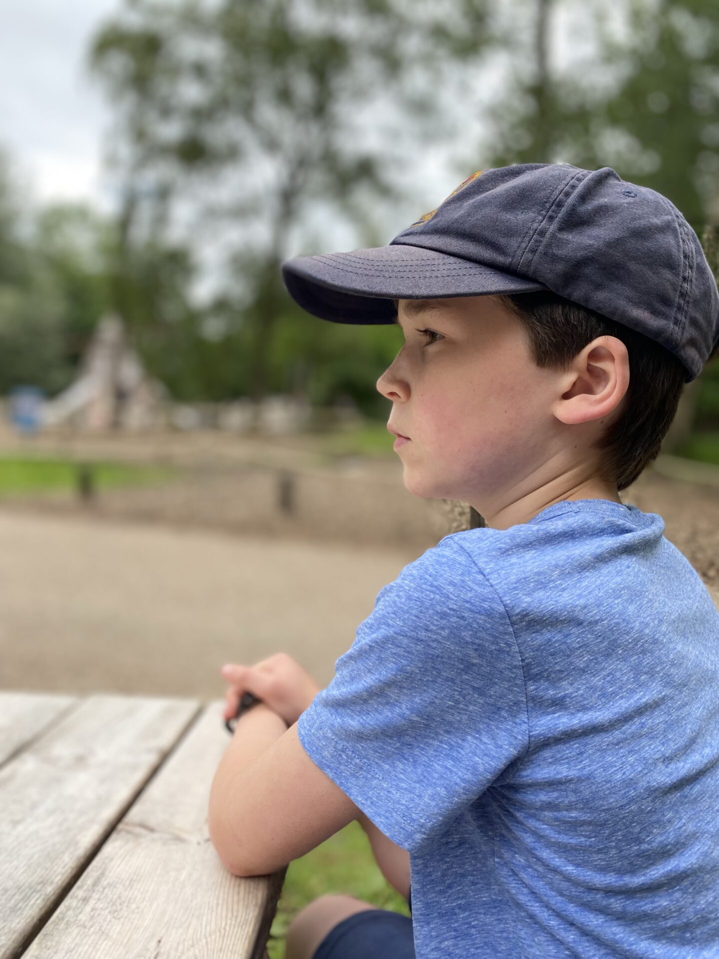 a boy sat on a bench at the playground 