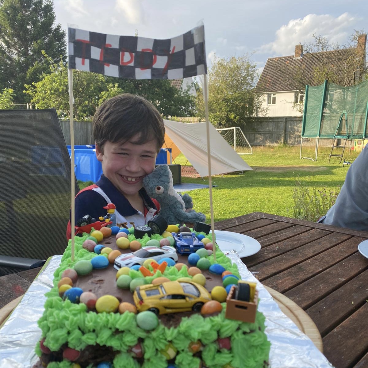 a young boy posing with is car race track birthday cake