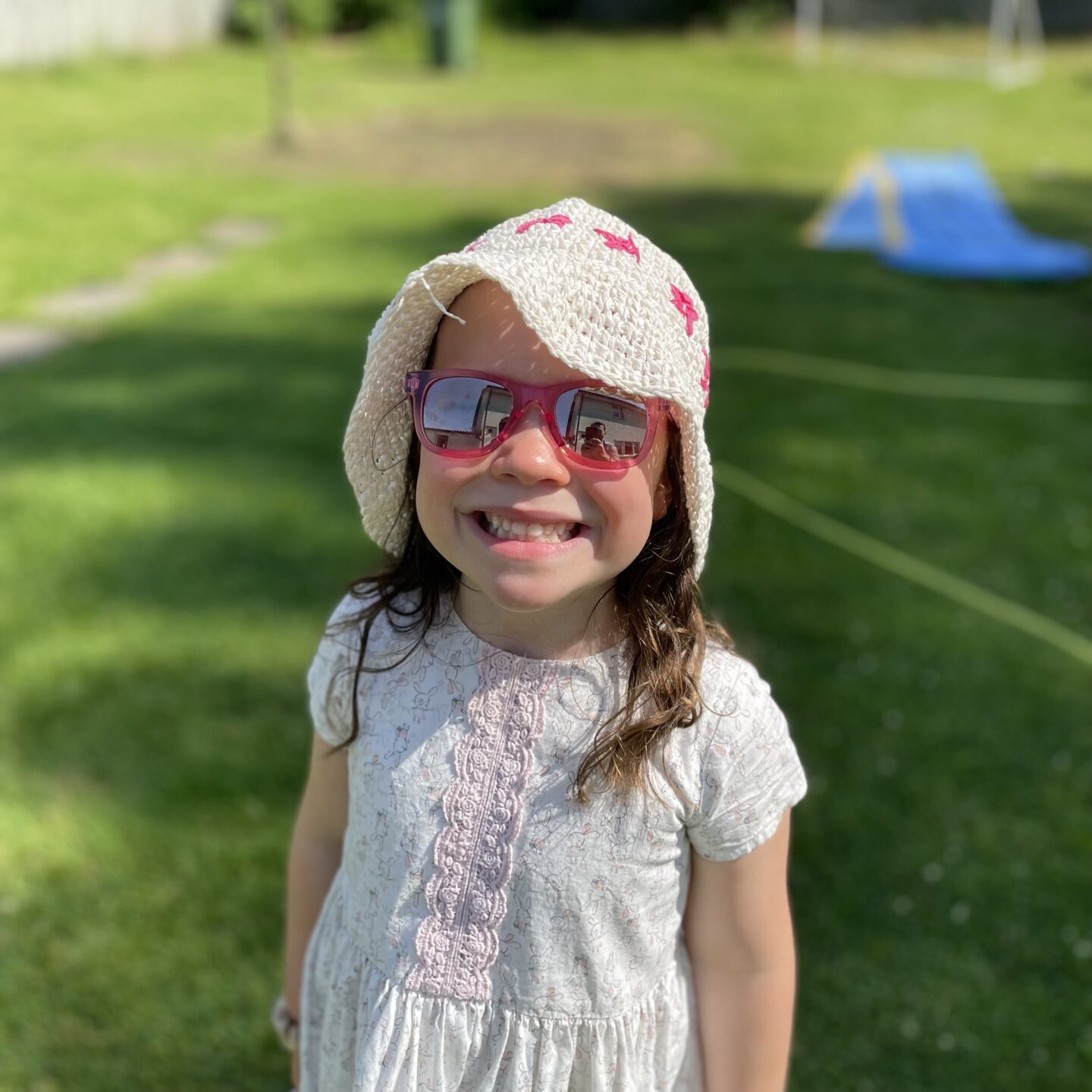 a small girl smiling at the camera with sunglasses on