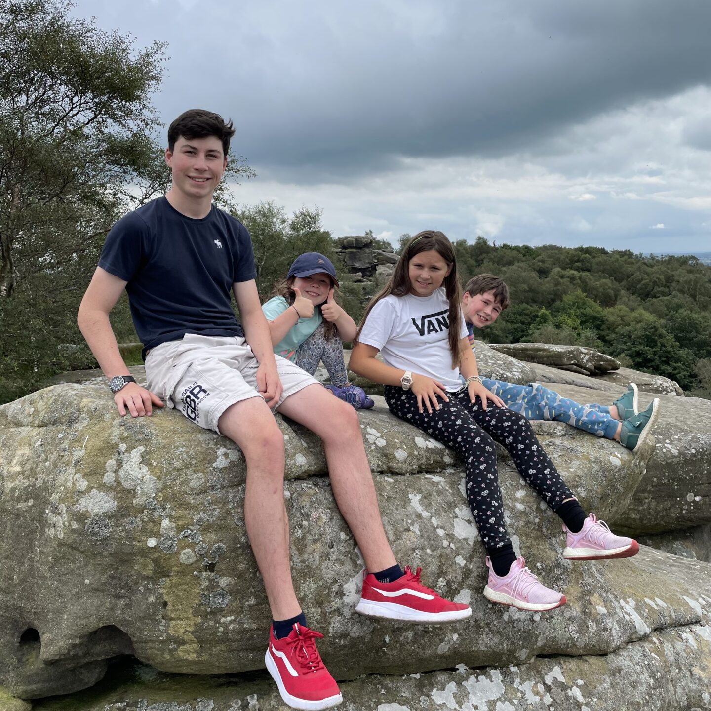 4 kids sat on top of a gritstone rock at Brimham rocks