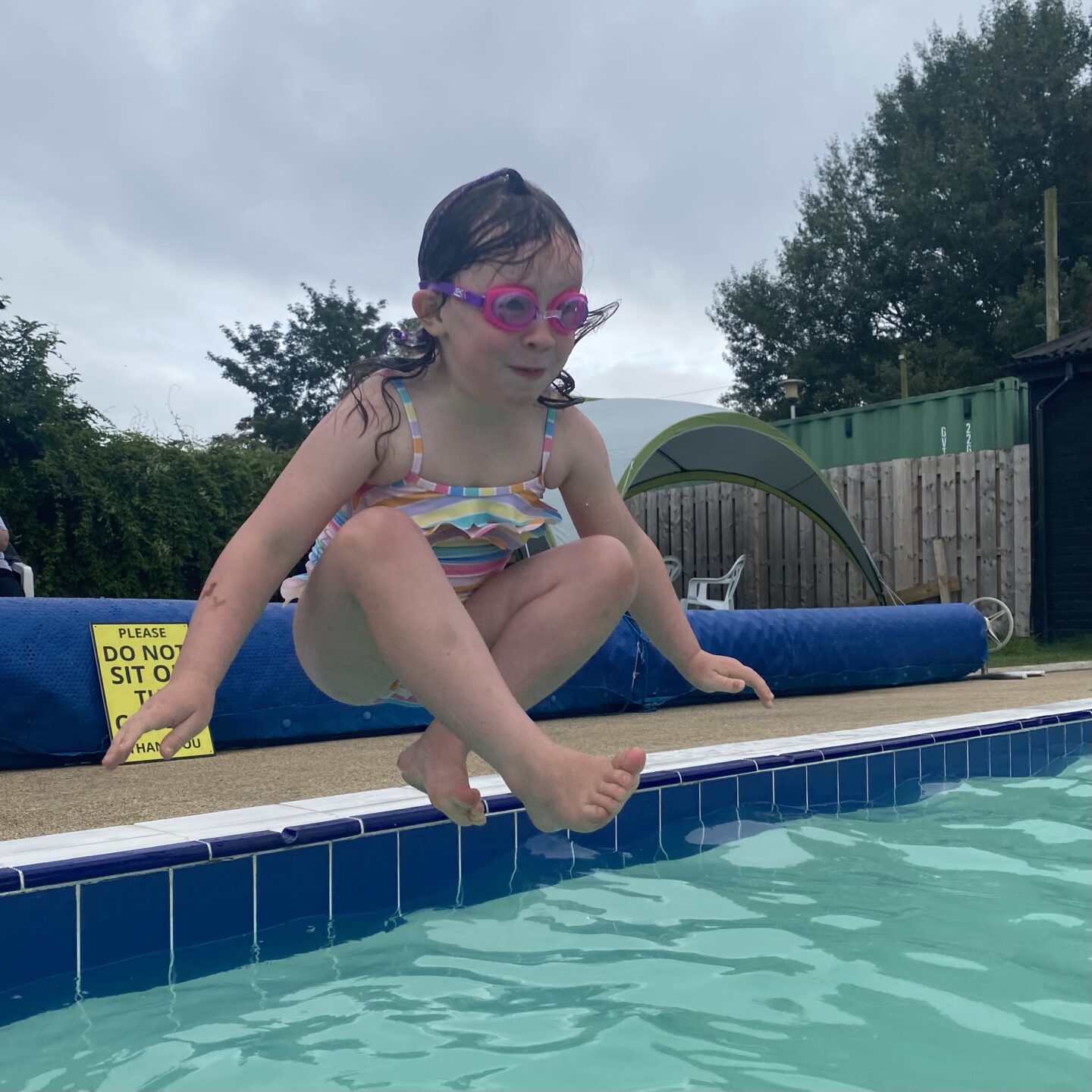 a girl jumping in the pool in a buddha pose