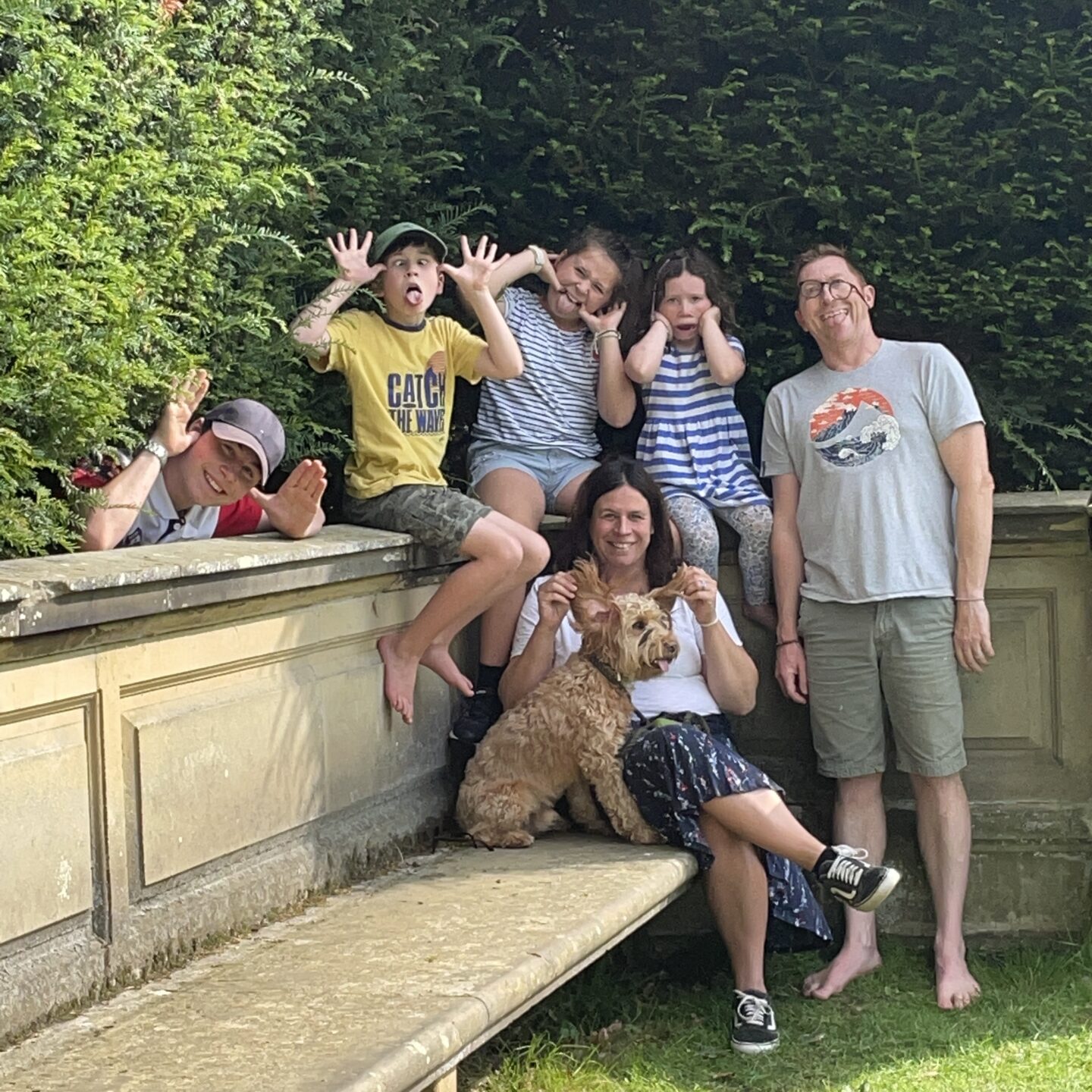 a silly family photo where 6 members are pulling funny faces together 