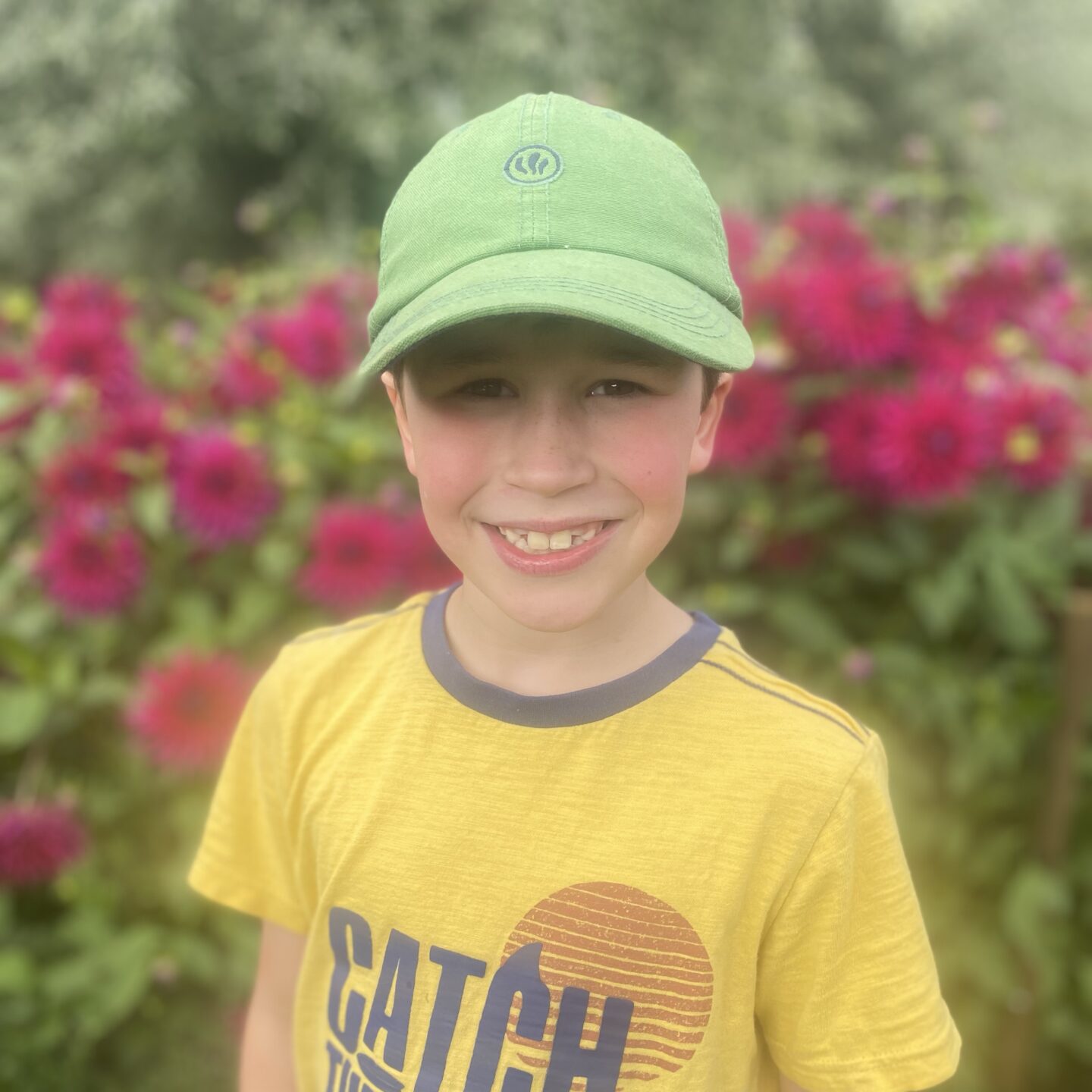 end of the summer holidays photo with a boy smiling by pink flowers 
