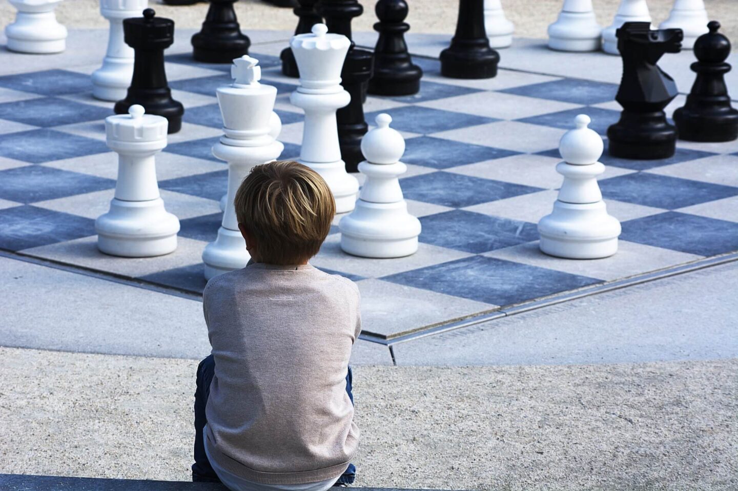 child develop critical thinking skills with a child sat looking at a giant chess set