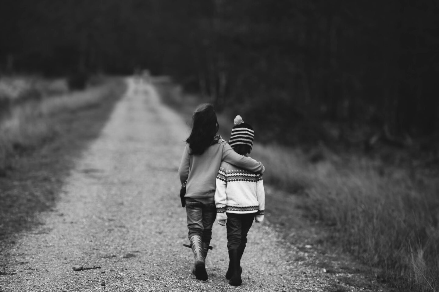 How to raise an optimistic child with 2 children walking up a track with one putting an arm around the other. 