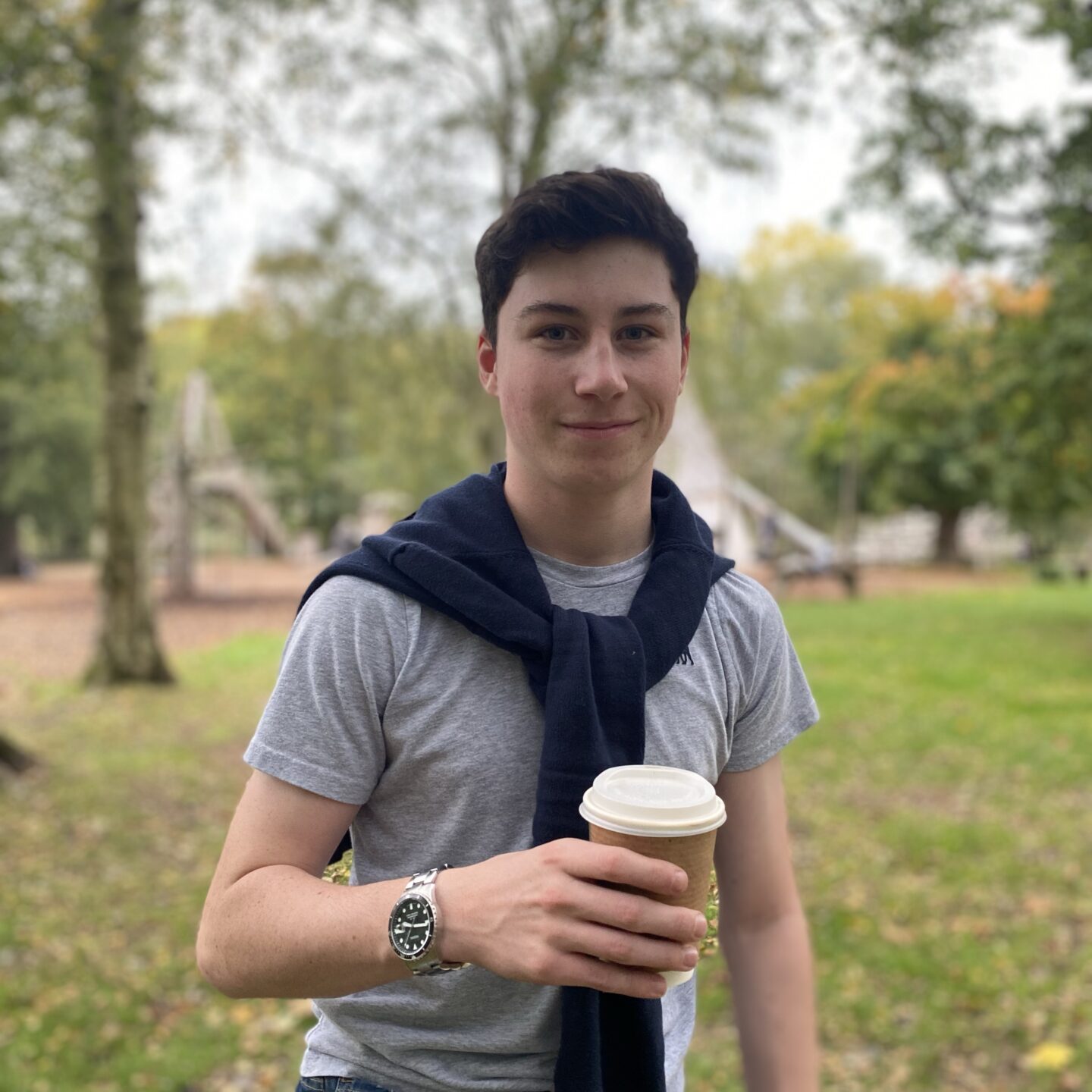 a teenage boy holding a cup of coffee