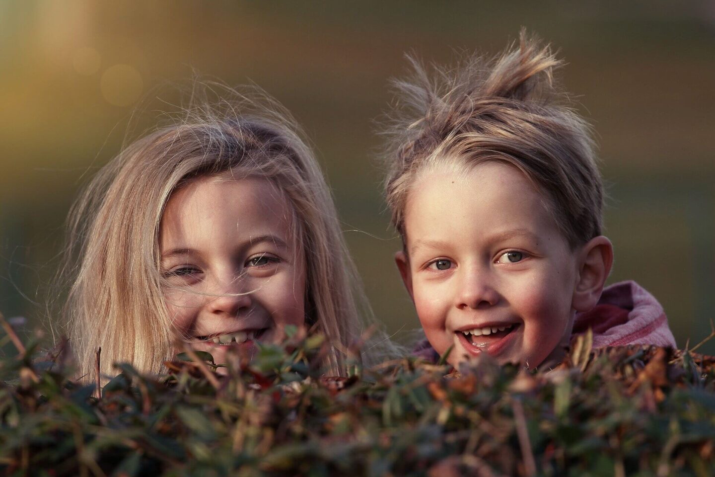 5 Screen Free Activities to Explore with Your Child with 2 children popping their heads over a hedge