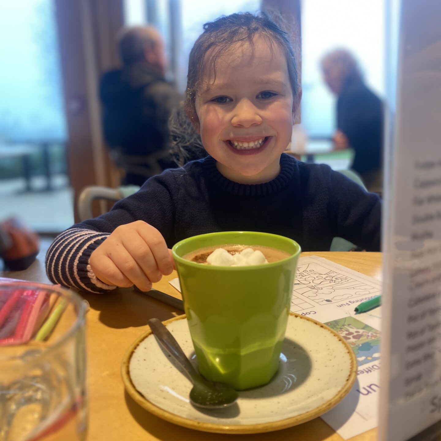 a young girl drinking hot chocolate in a cafe