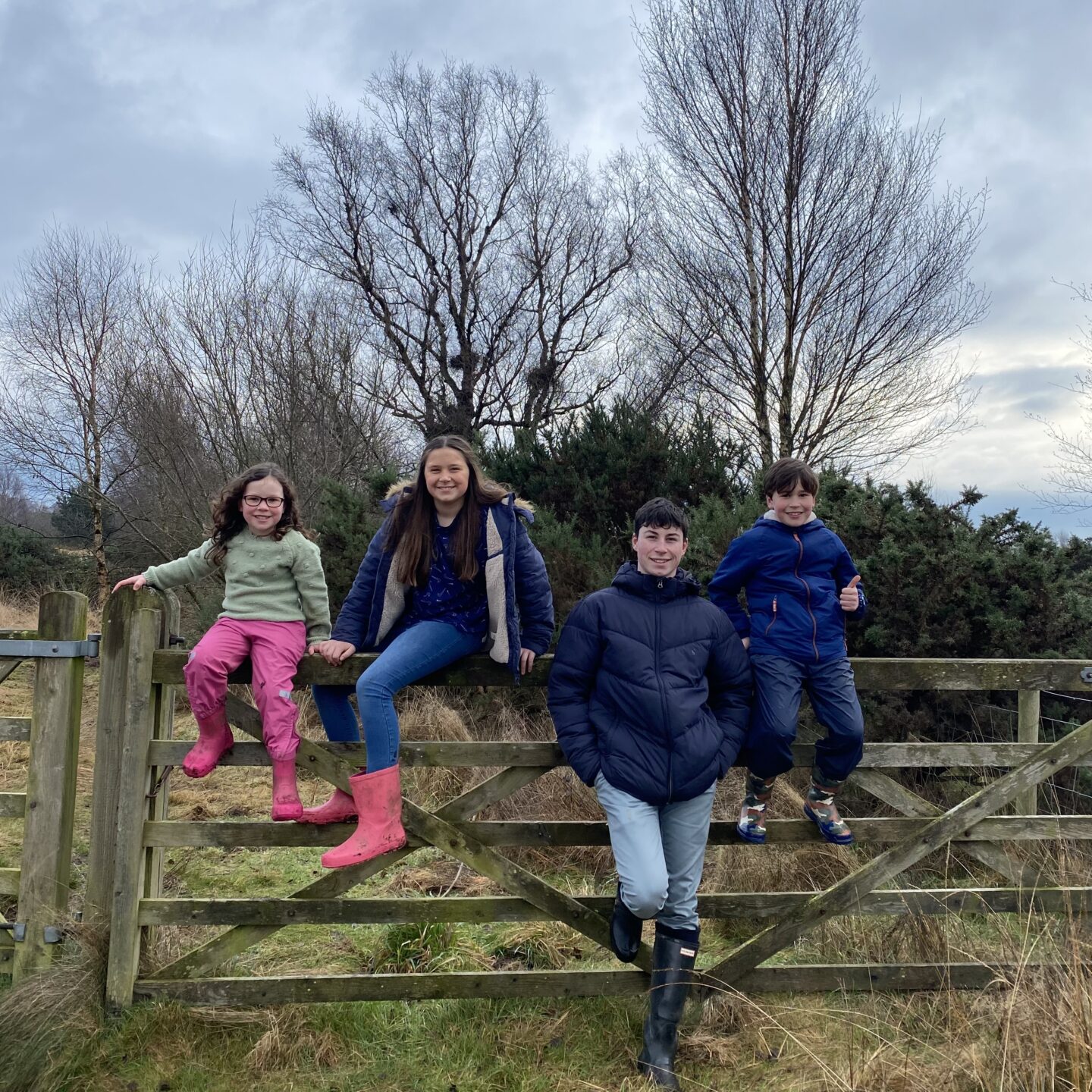 all 4 children sat posing for a photo by a gate