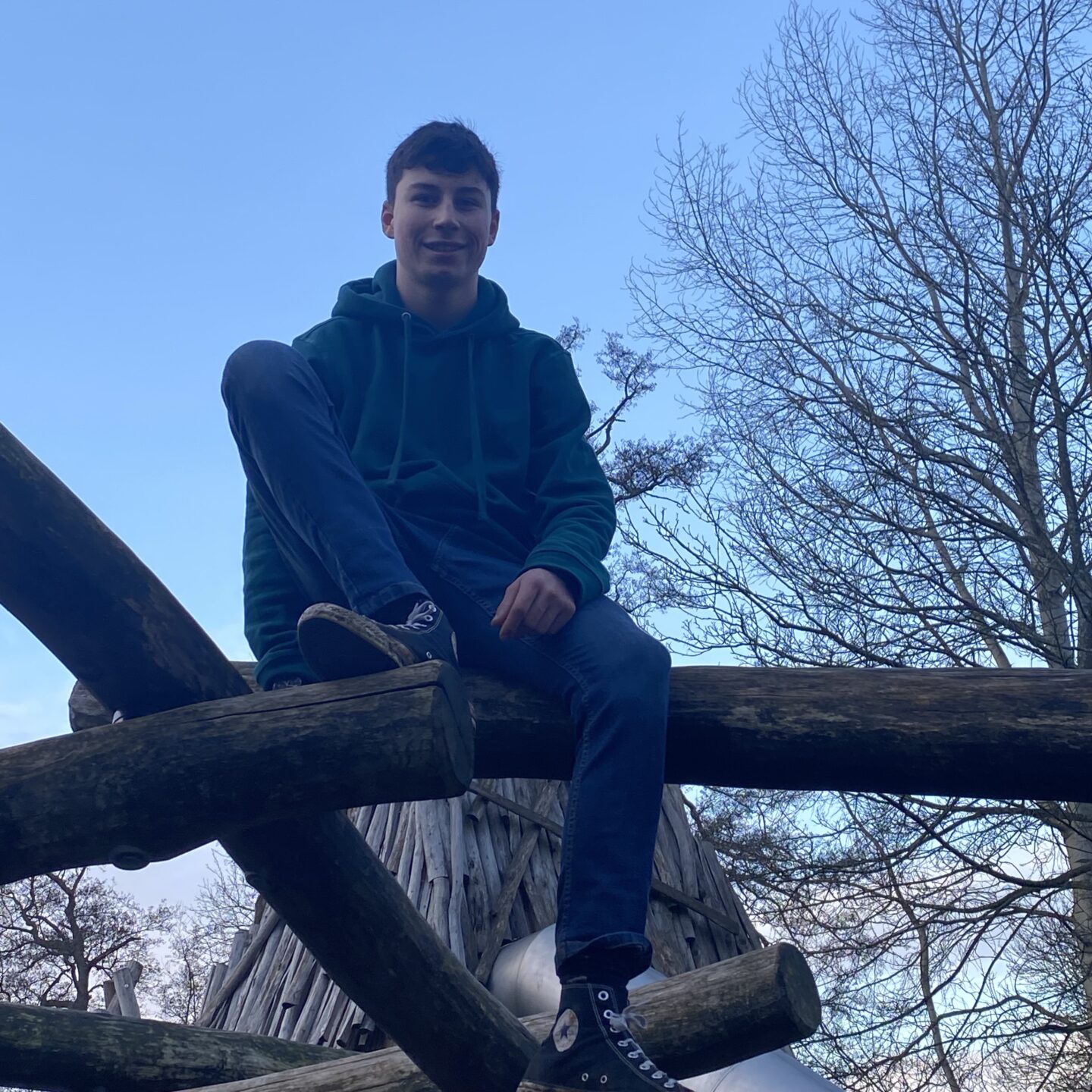 New Year walk with a teenage boy sat on a wooden play park obstacle
