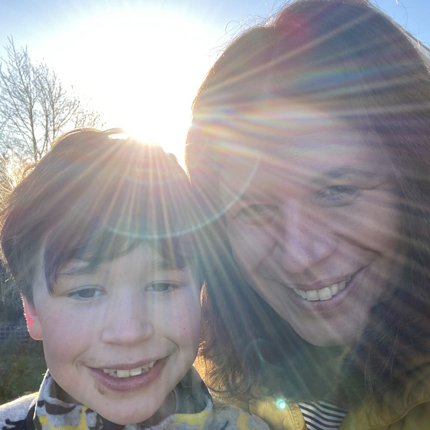 A young boy and Mum smiling in the Winter sunshine of teh garden