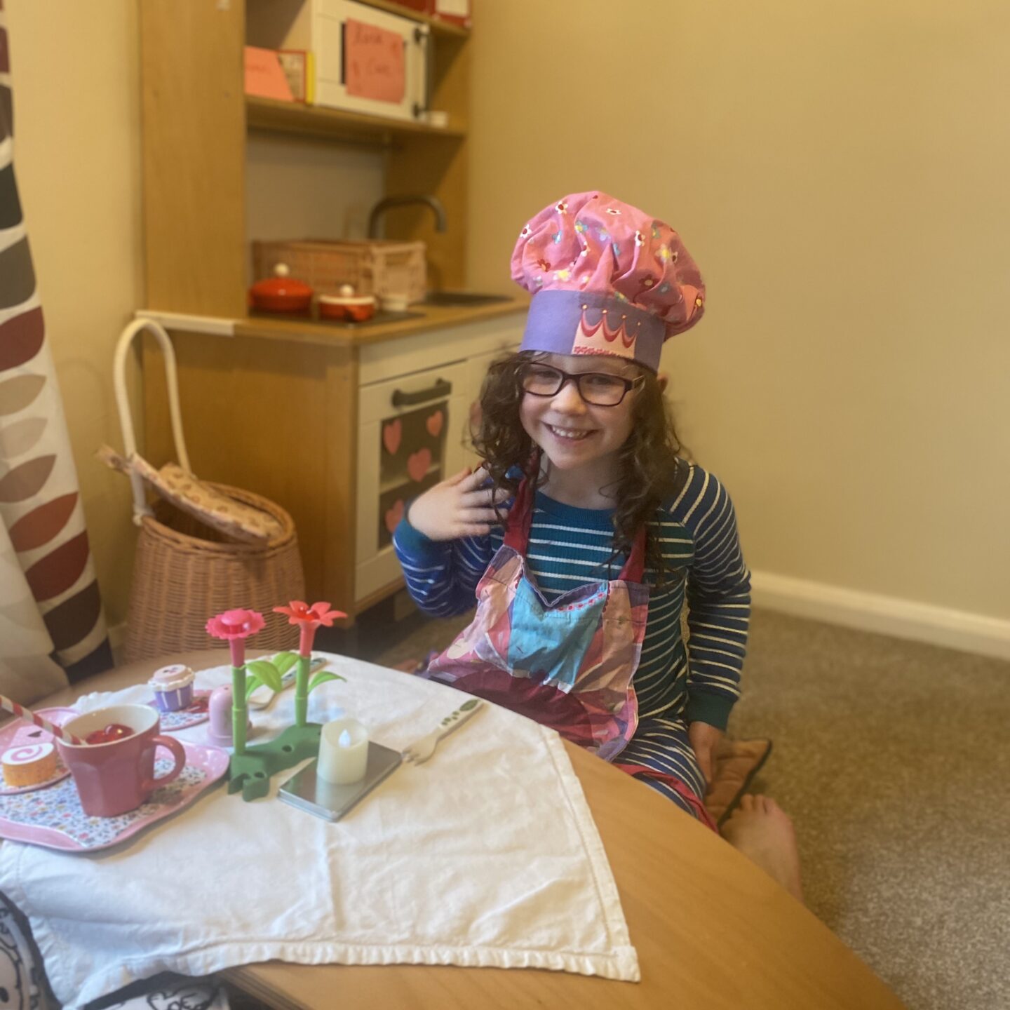 a young girl playing cafes in a toy kitchen