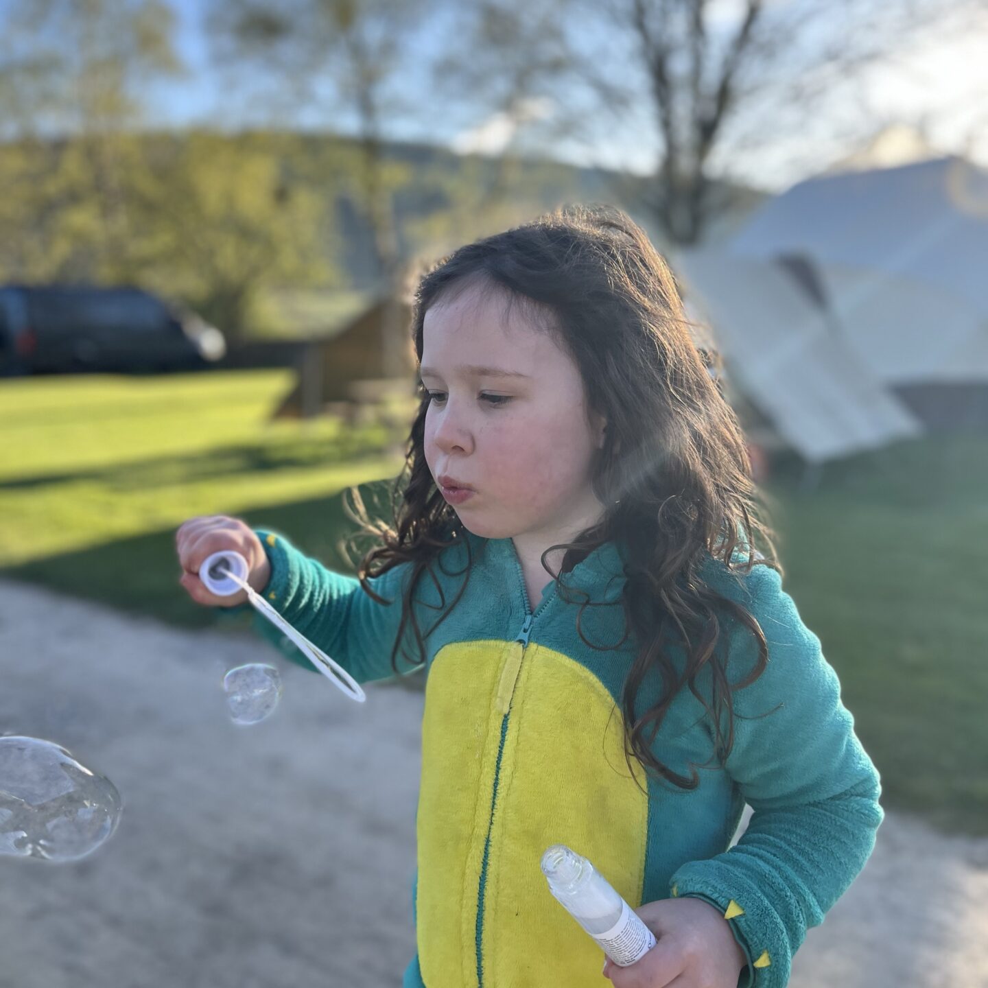 Break in the dales - a girl blowing bubbles on a campsite dressed in a fluffy  onesie 