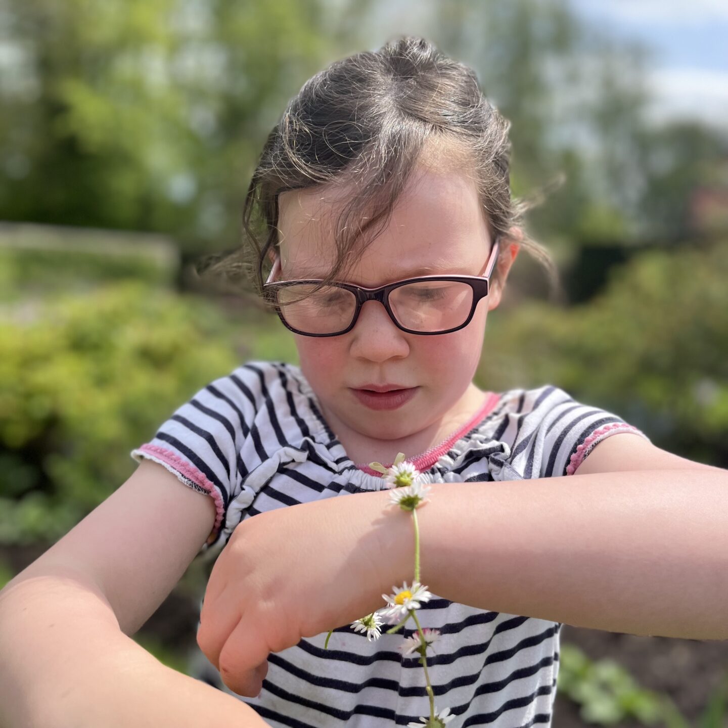 a young girl looking at a daisy bracelet