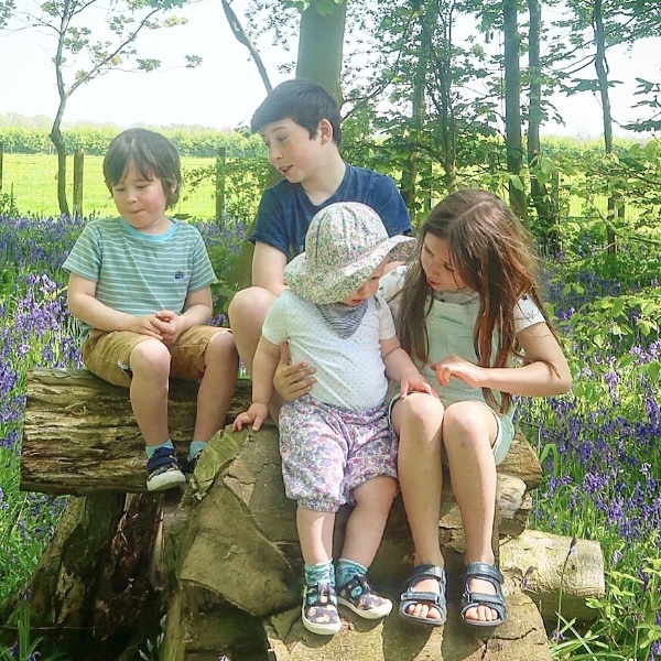 4 kids sat on a log in the woods