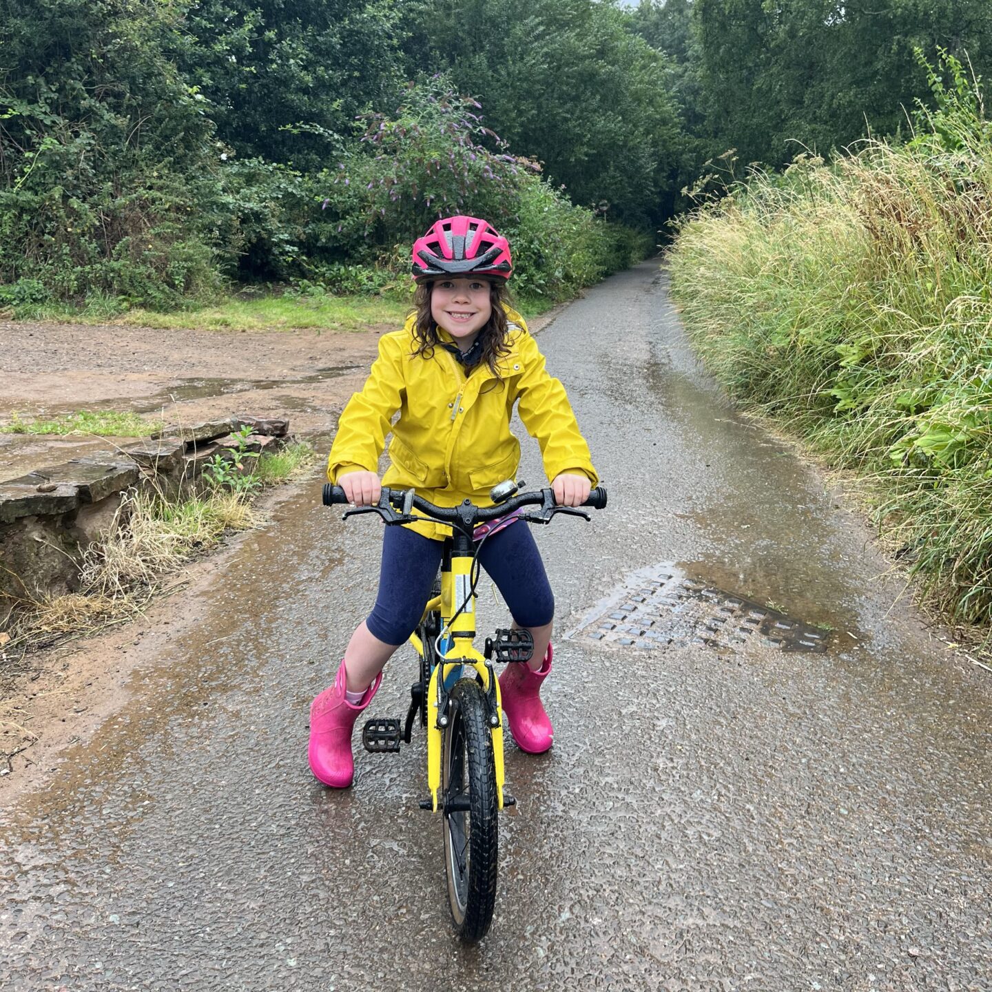 summer days at hoe with a girl on her bile in a yellow coat and pink wellies