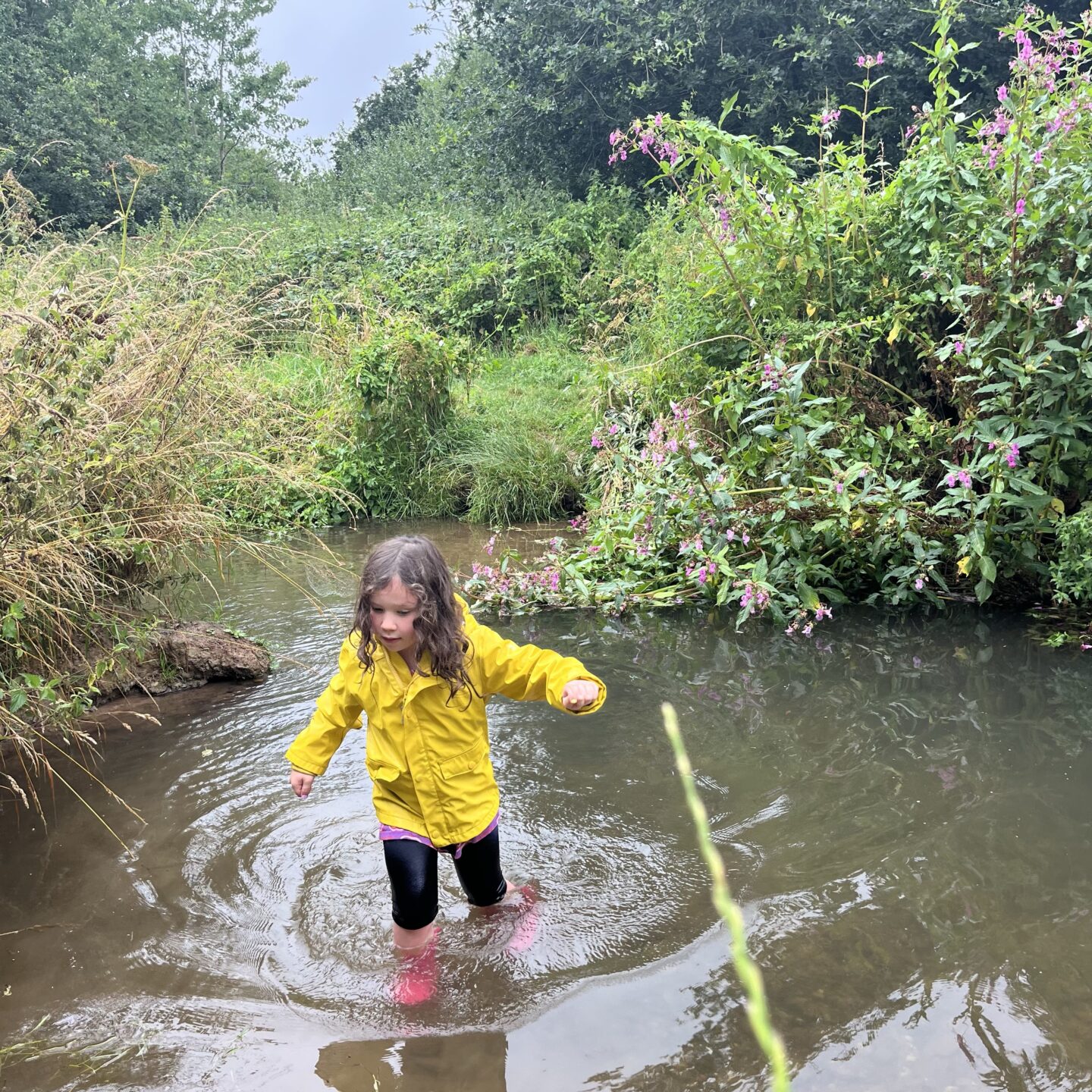 summer home days with a girl in the river with her wellies