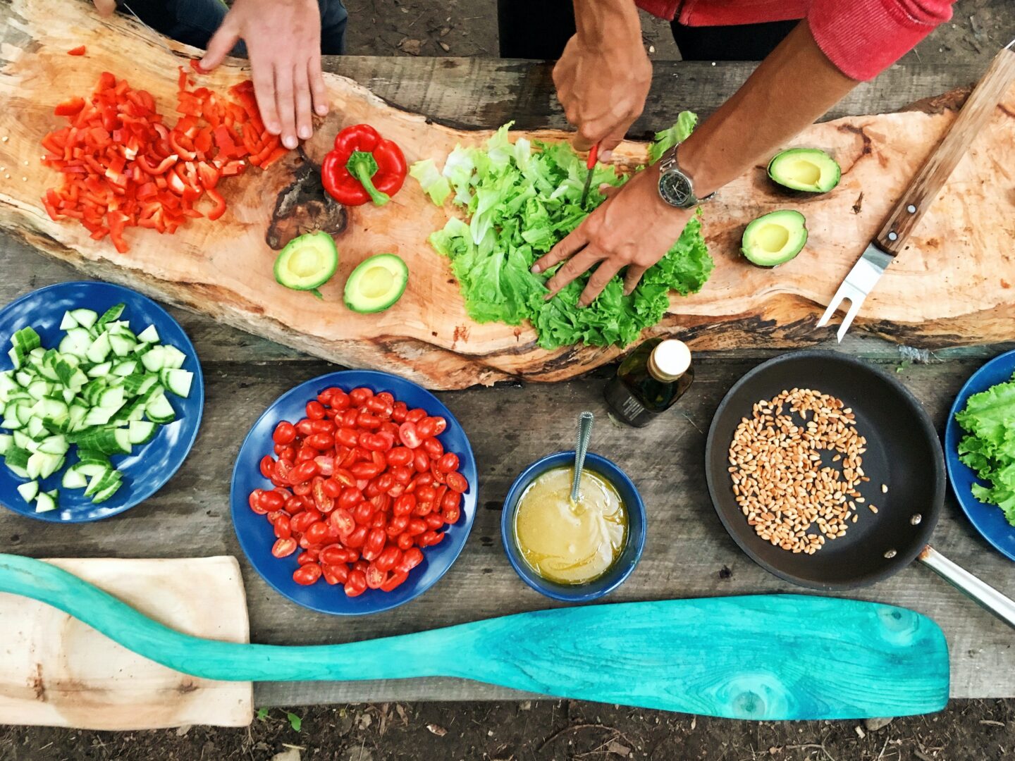cooking from scratch - some fresh ingredients on a wooden table with chefs cutting up salad 