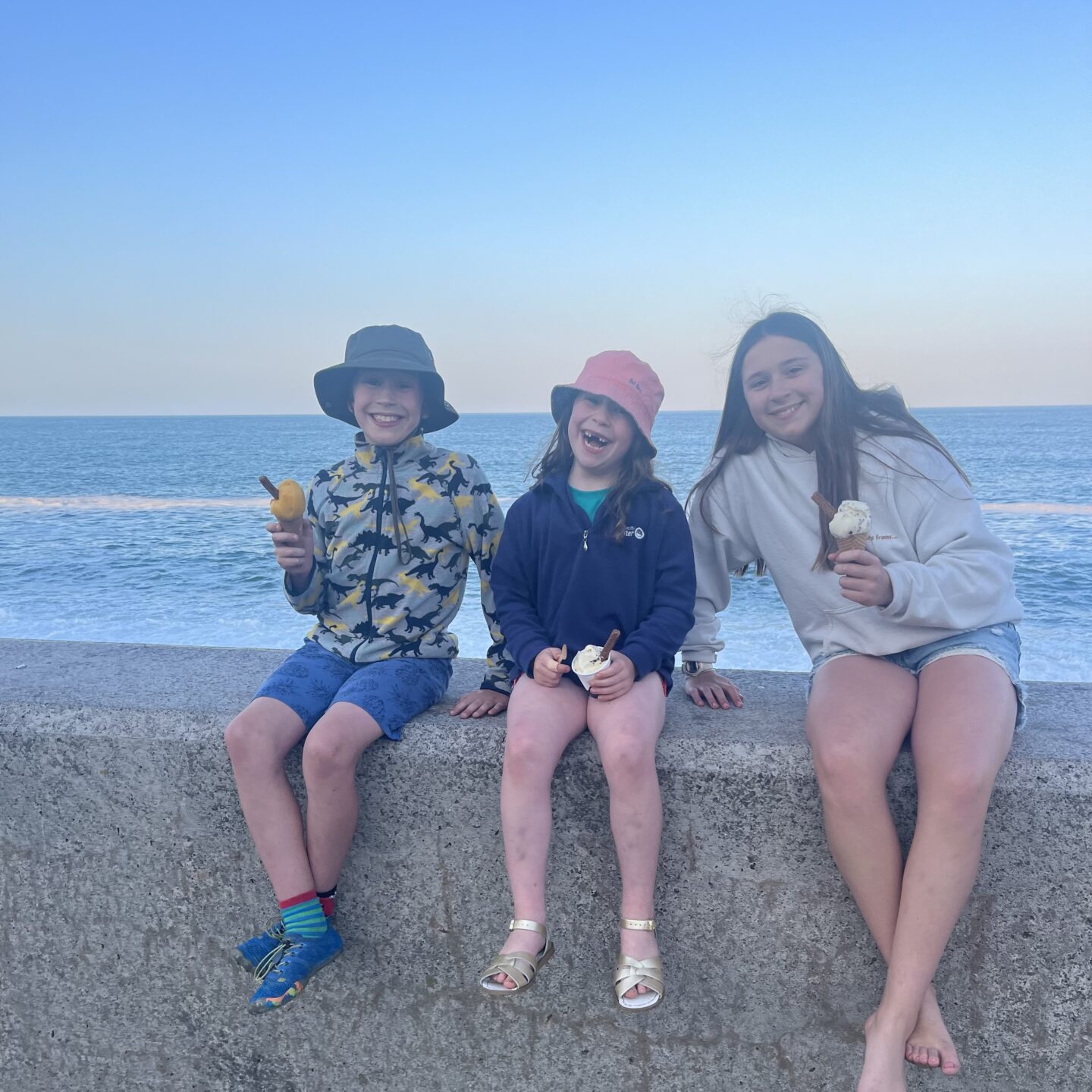 3 kids on a seafront wall 