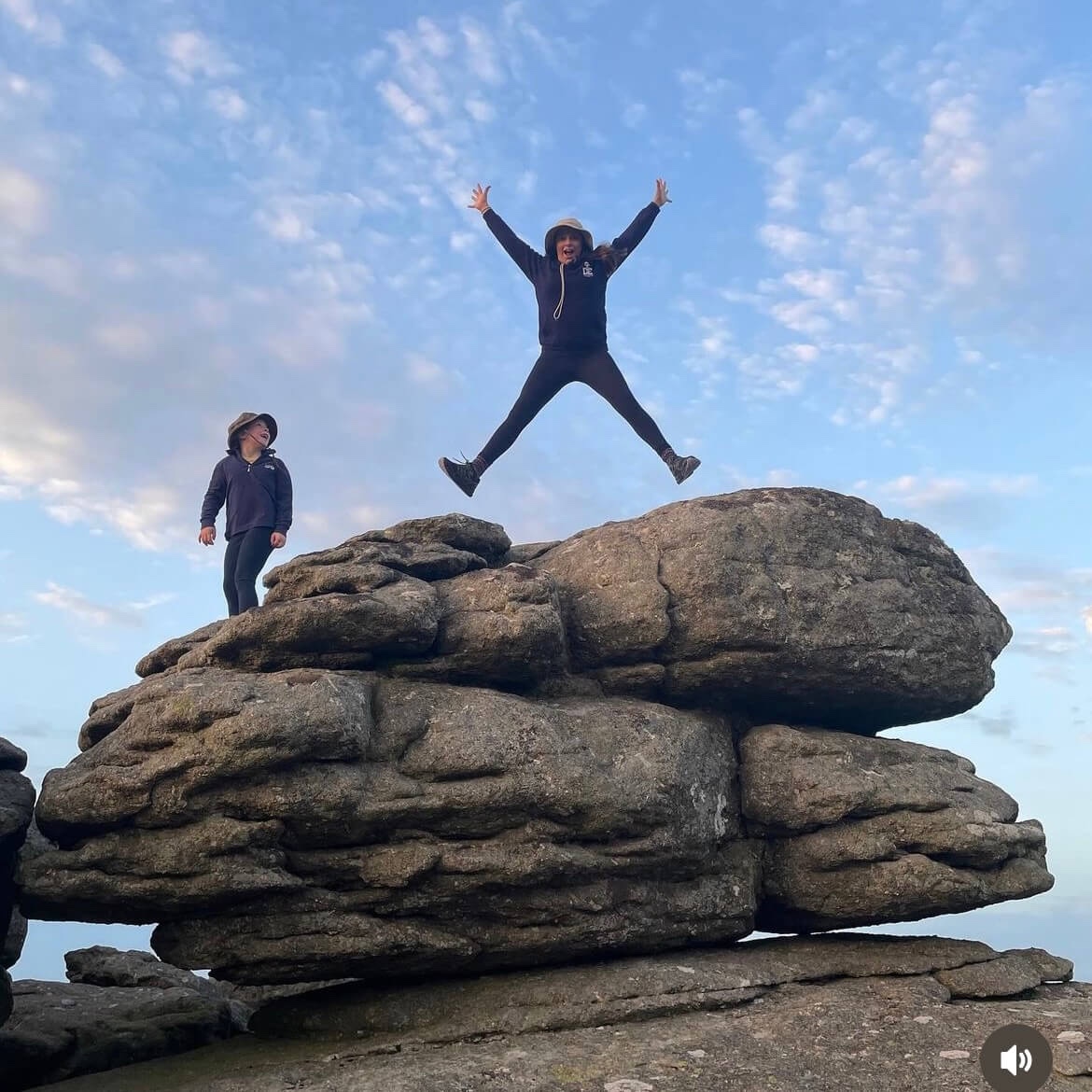 Two girls jumping on the rocks when taking family walks in Haytor and Hound Tor in Dartmoor  