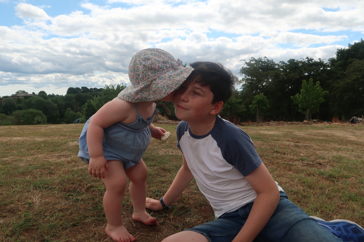 a baby kissing her older sibling 