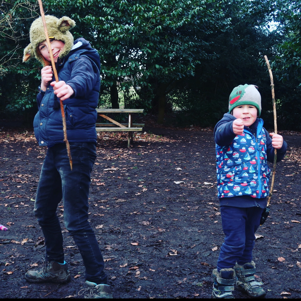 age gap parentimg - 2 boys with bows in the woods 