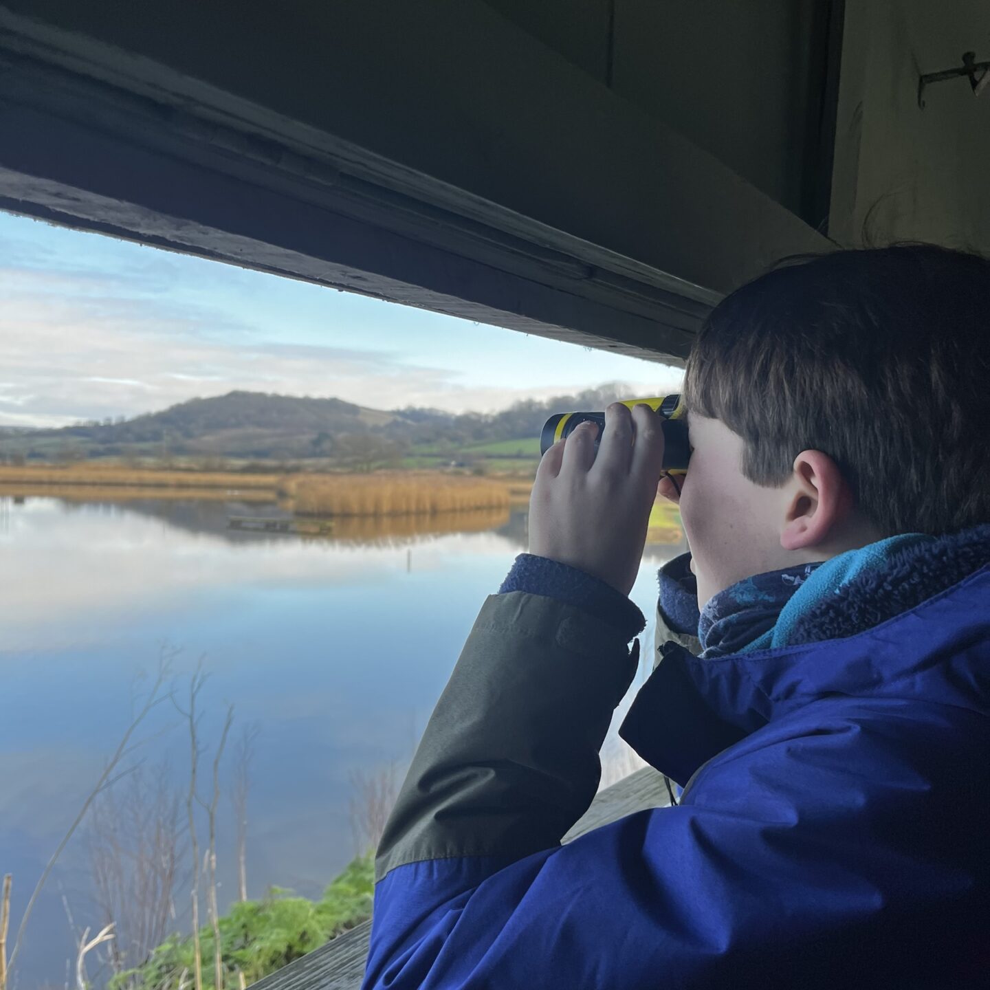 A boy in a hide,bird watching over a lake - Easter days out in Devon