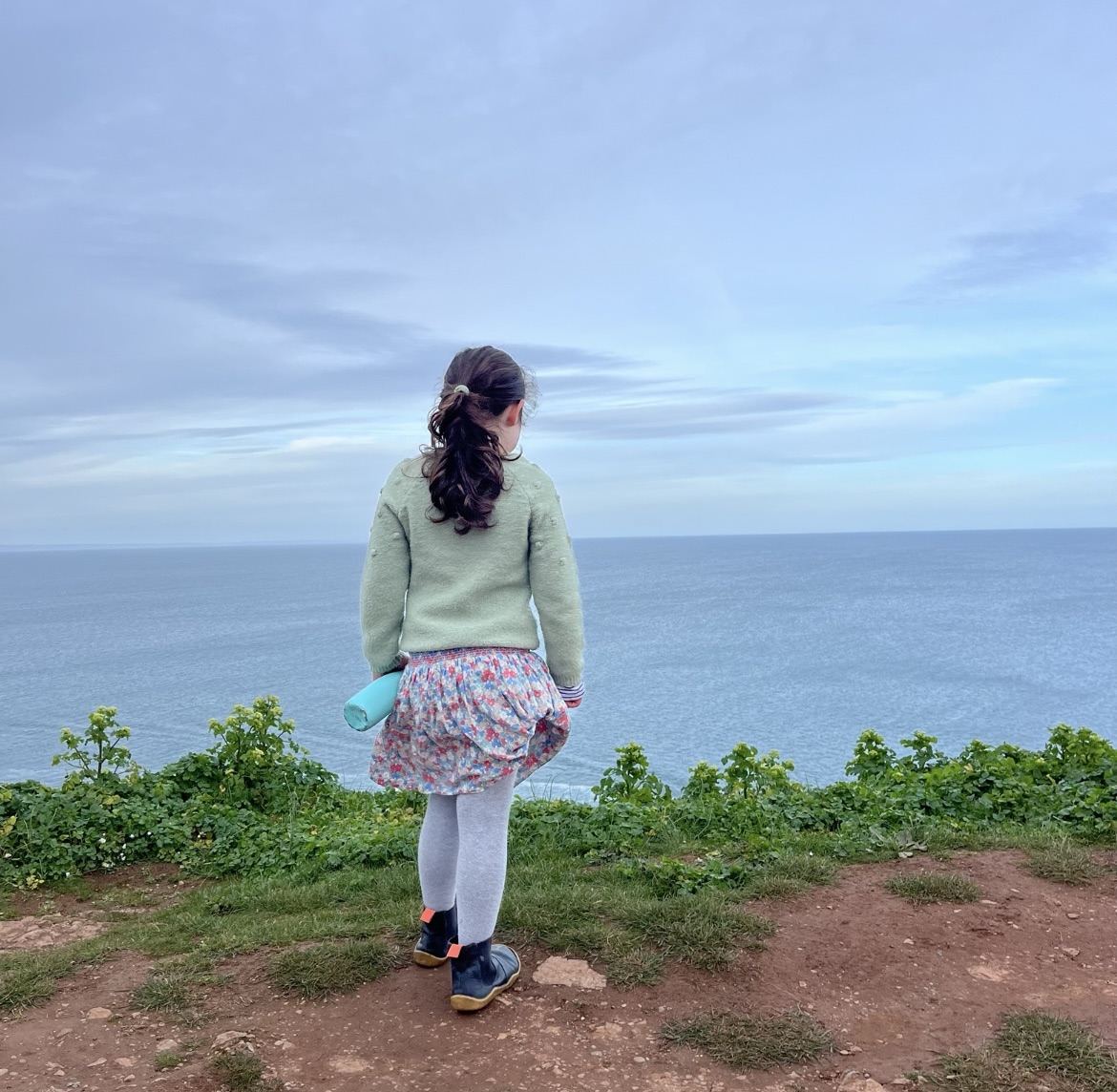 May Half term days out in Devon with a girl stood at a headland looking at the view 