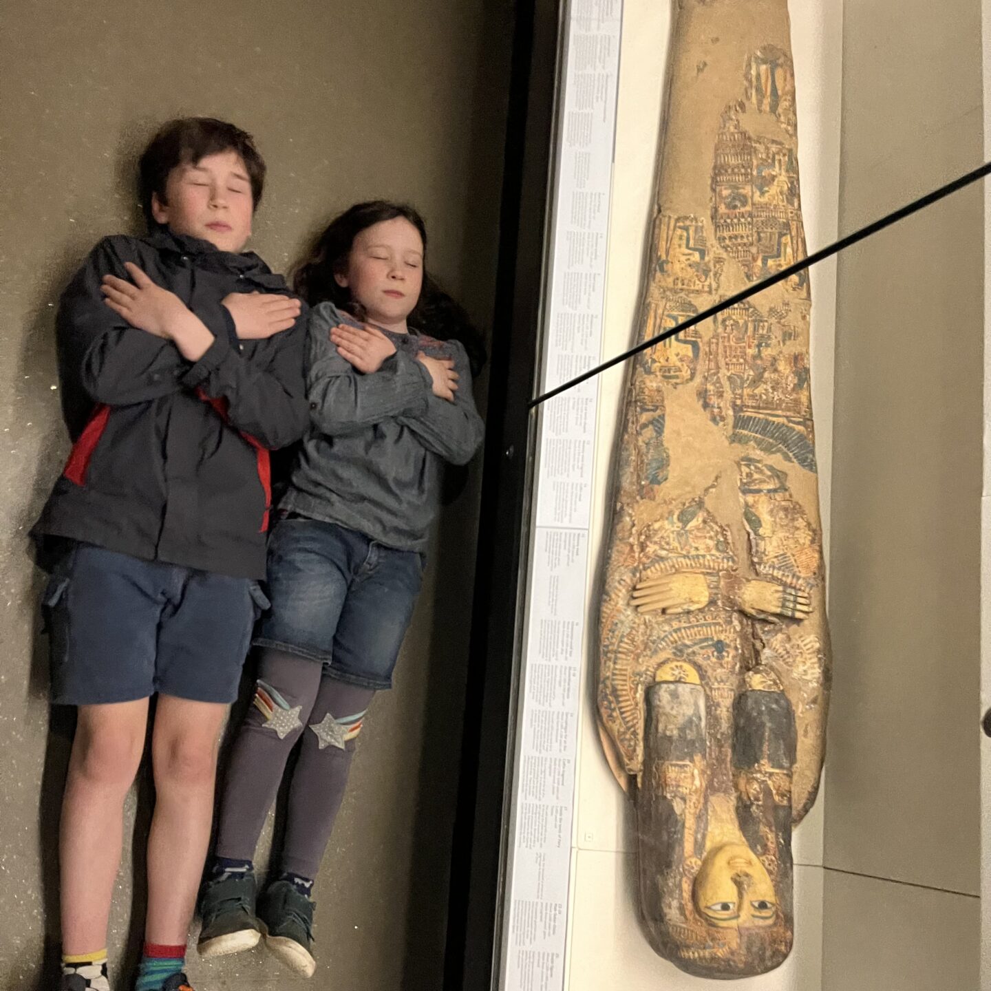 2 kids lying next to Egyptian coffin in Exeter Ramm