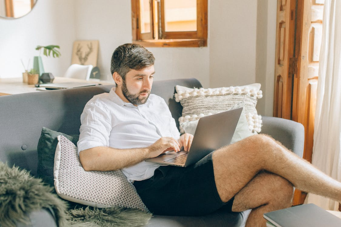 A man sat on a sofa on a laptop researching how to make your storage room better