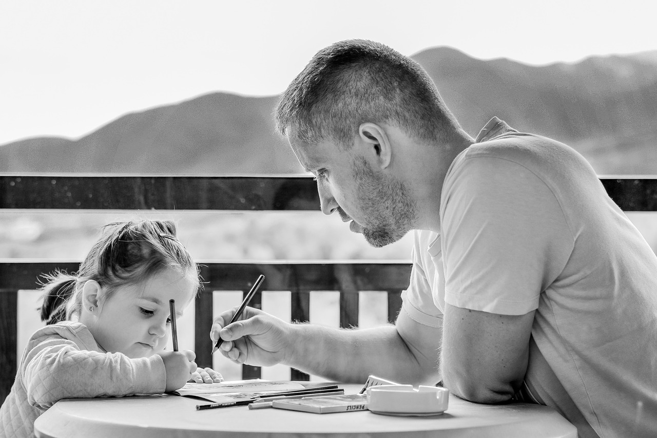 a dad and a daughter writing at a desk building on patience