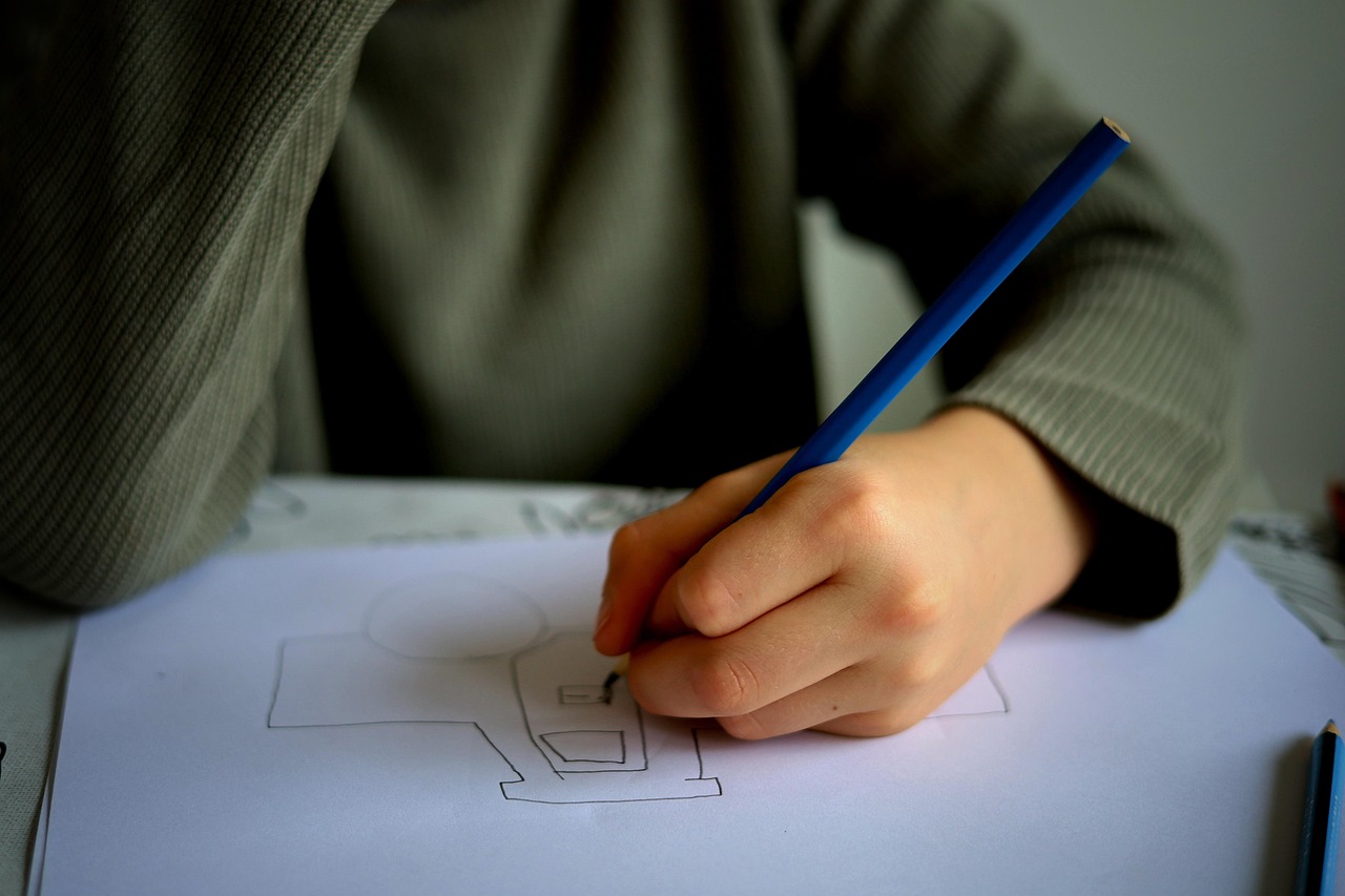 a child drawing a vehicle with a blue pencil for an article on helping kids learn from mistakes